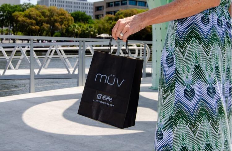 Photo of a woman's hand holding a MUV shopping bag