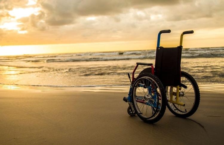 A wheelchair positioned on the beach during sunset